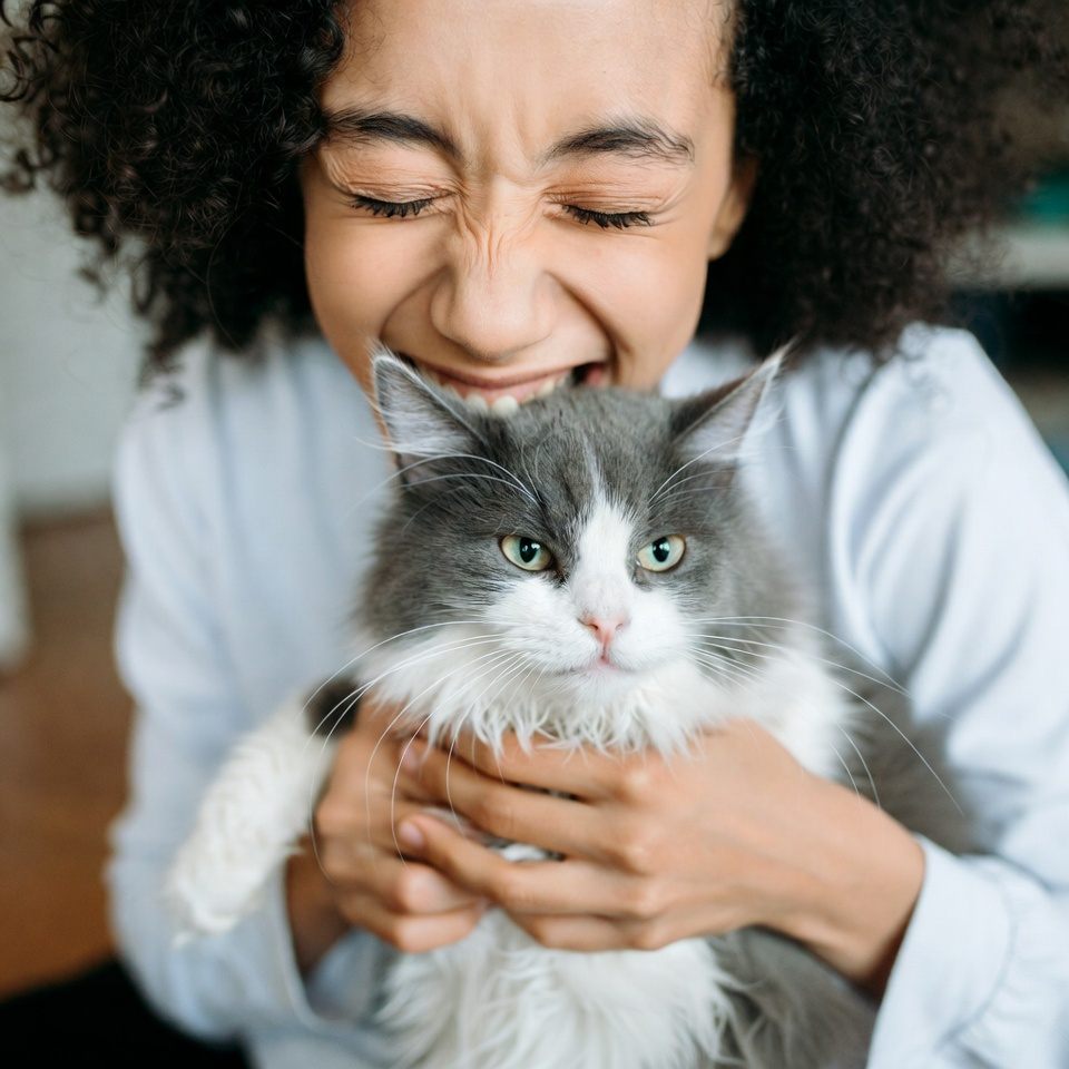 Frau umarmt lachend ihre Katze